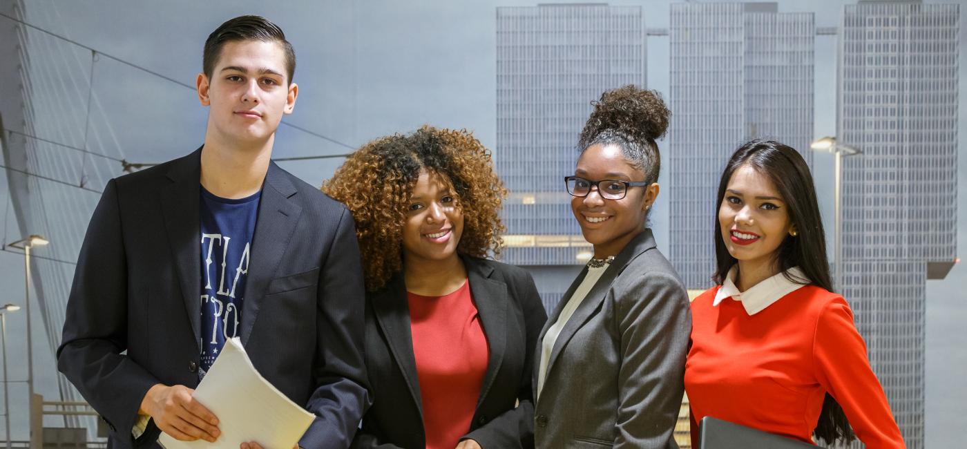 Vier studenten, drie vrouwen en een man, kijken in camera. 